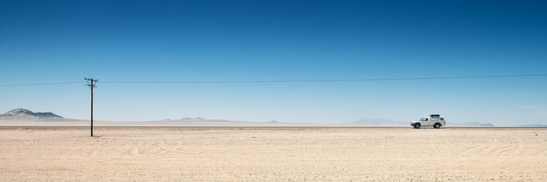 grafisches Bildmotiv von Geländewagen und Strommasten in der Weite Namibias | Fotograf Ulm, Reisereportage Namibia